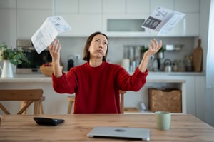 woman in kitchen throwing bills up in the air in frustration